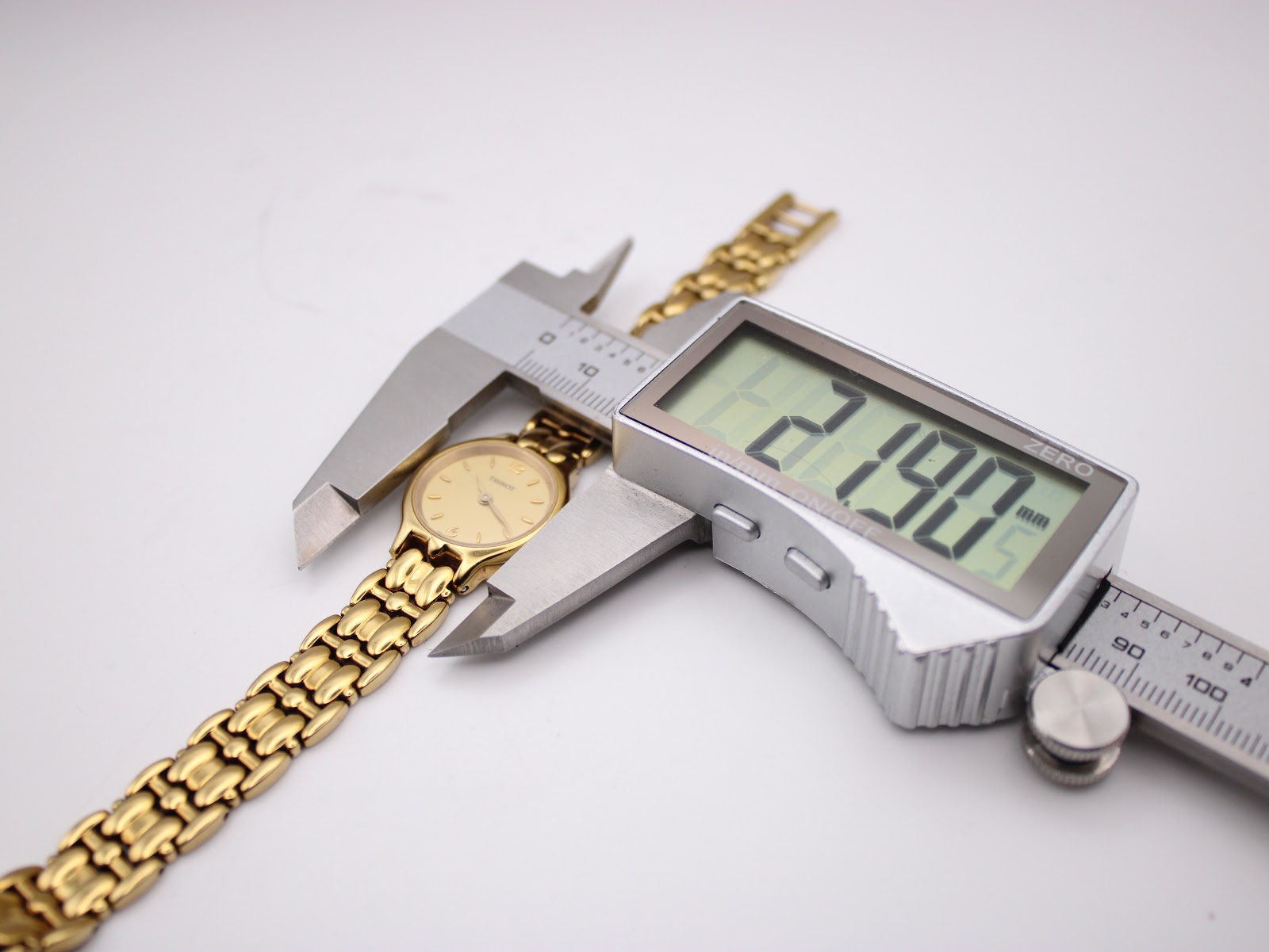 A digital caliper measuring the case diameter of the Tissot E421K at 21.90mm.