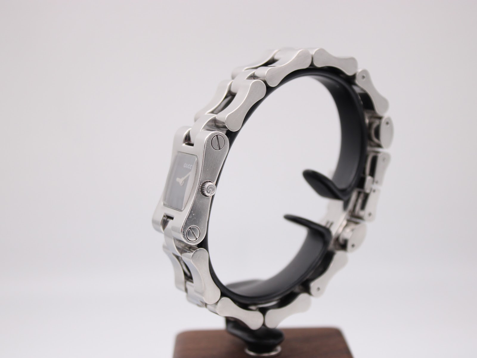 Side view of the Gucci 2300L on a stand, showing the case profile and integrated link bracelet.