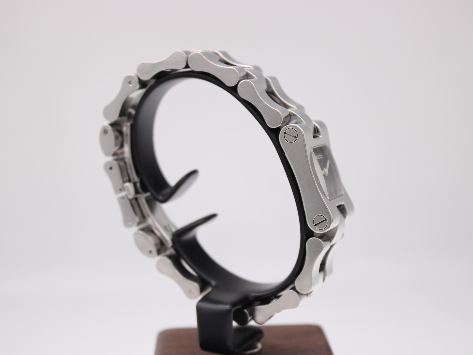 Angled side view of the Gucci 2300L on a stand, highlighting the bracelet construction and case design.