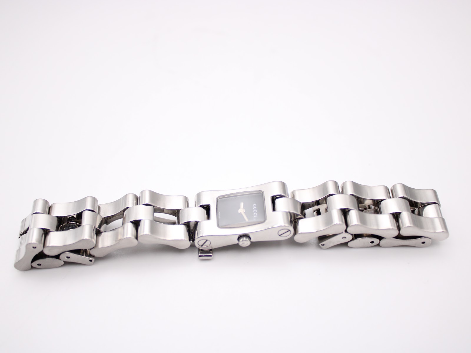 Angled top view of the Gucci 2300L watch with its stainless steel link bracelet laid out, showing the case and bracelet details.