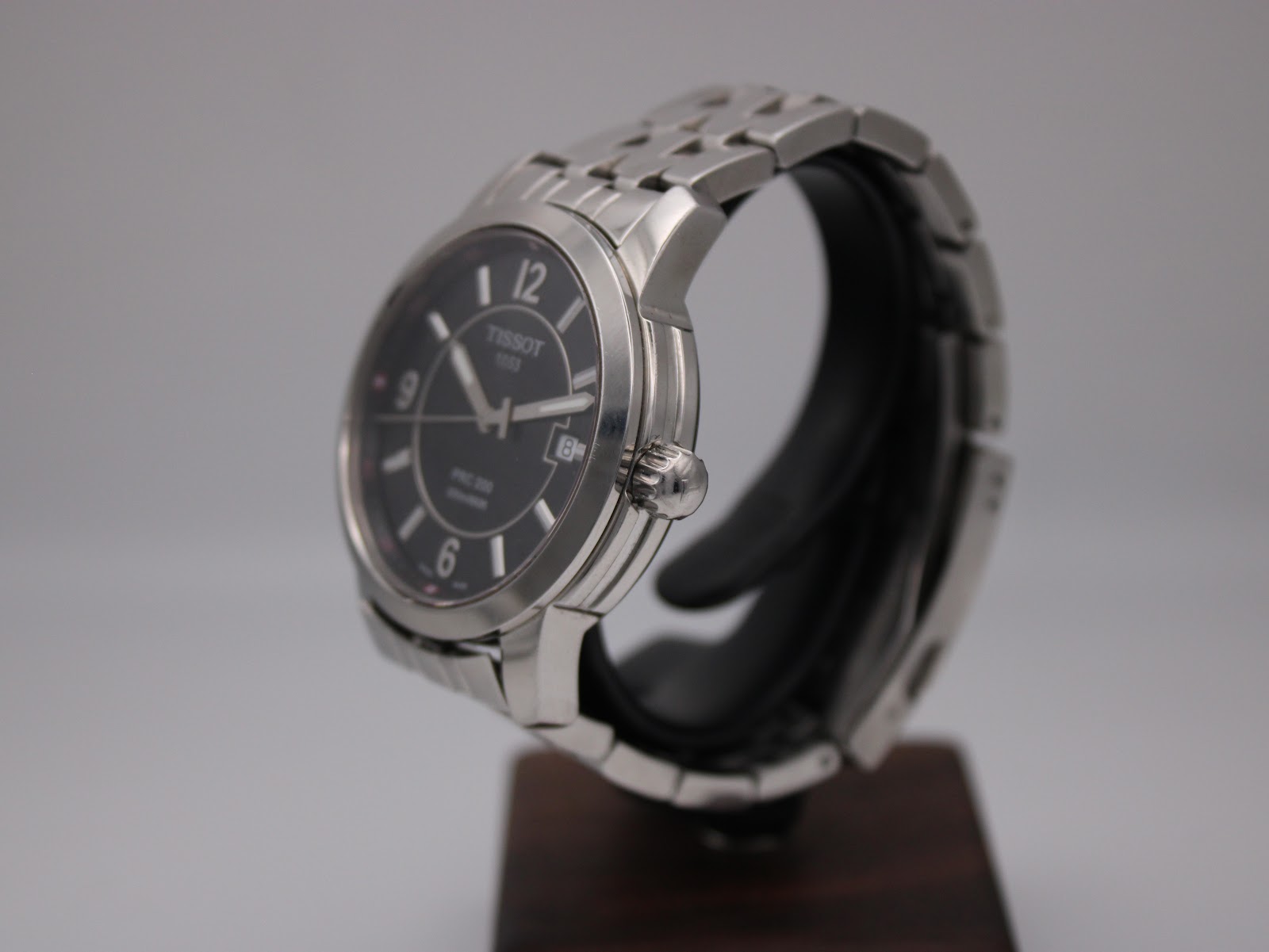 Angled side view of the Tissot PRC 200 watch, highlighting the polished and brushed stainless steel case and crown.