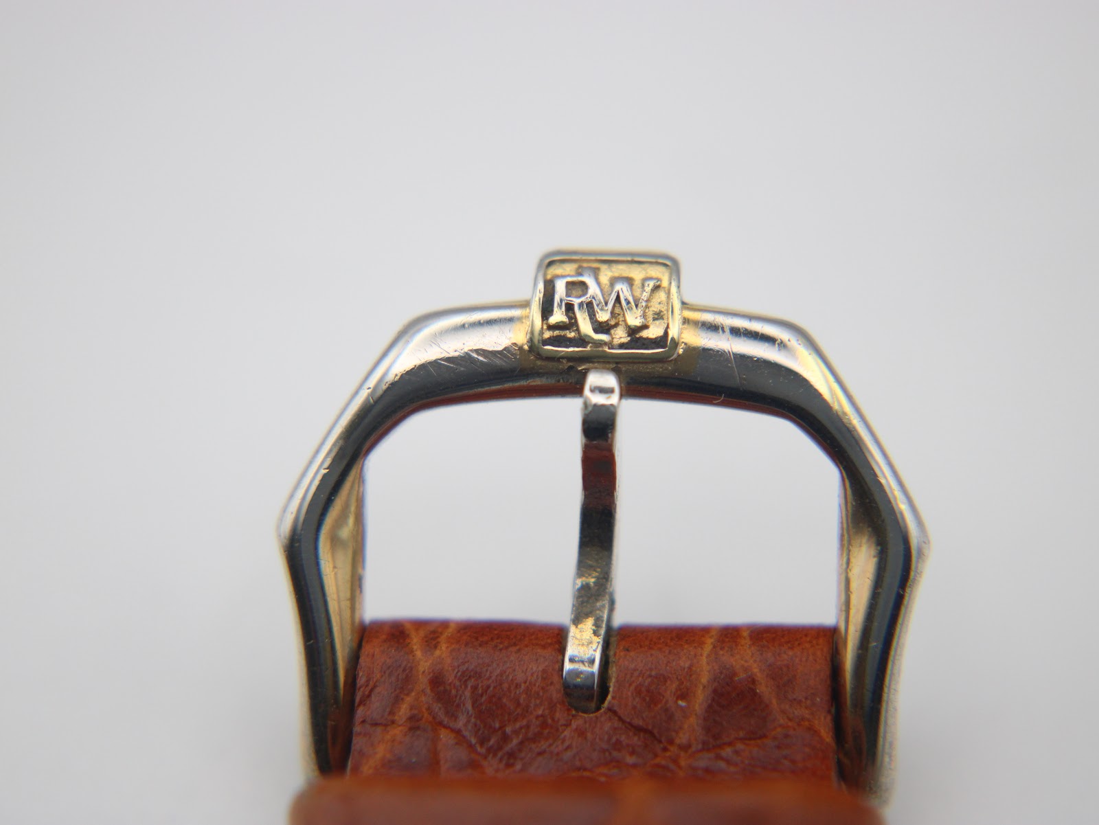 Detailed close-up of the gold-tone buckle, clearly showing the 'RW' Raymond Weil logo.